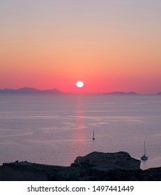Griekenland Santorini Zonsondergang vanaf de heuveltop met bergen op de achtergrond en boten op zee op de voorgrond