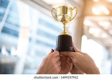 Campeón trofeo de oro para el ganador con las manos del jugador deportivo en el fondo del estadio deportivo. Concepto de éxito y logro. Tema de premio de deporte y copa. Premio de fútbol americano y premio de juego de partido