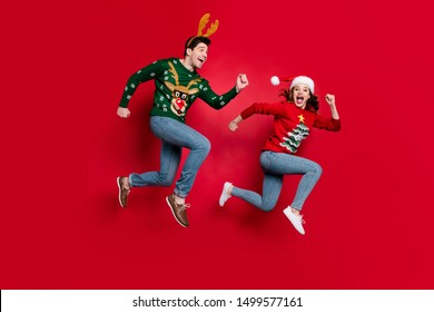 Foto seluruh tubuh pasangan melompat kagum bersemangat dengan harga x-mas bergegas belanja memakai ornamen jelek jumper terisolasi latar belakang warna merah