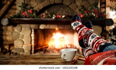 Kaki wanita dengan kaus kaki dan perapian natal