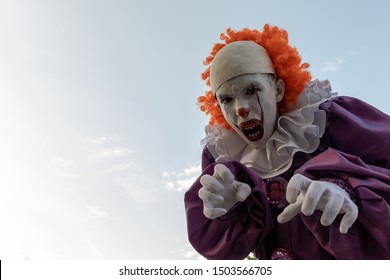 Chico adolescente disfrazado de payaso con dientes afilados. Cosplay para celebrar Halloween o una fiesta de disfraces de héroes terribles. Fondo de cielo, espacio de copia.