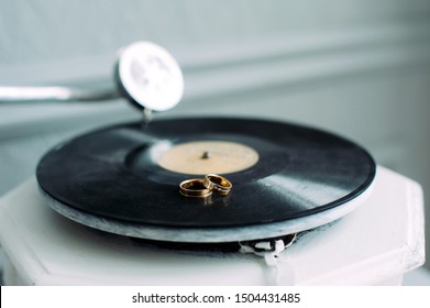 Wedding rings on the gramophone, close-up. Rings of the bride and groom on the music disc. Two gold rings on the phonograph. Wedding theme. Space for text.