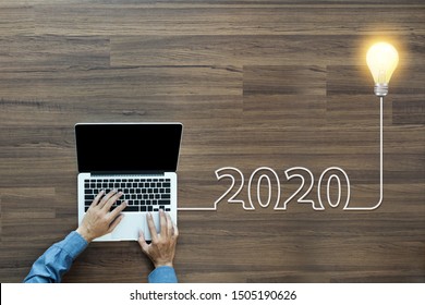 Creatief gloeilampenidee 2020 nieuwjaar, met zakenman die op laptop pc werkt, bovenaanzicht van bovenaf