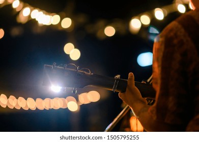 Man speelt akoestische gitaar op openluchtconcert met een microfoonstandaard vooraan, muzikaal concept.