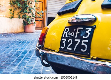 Uitstekende gele auto in de straat met een oude autoplaat in Rome.