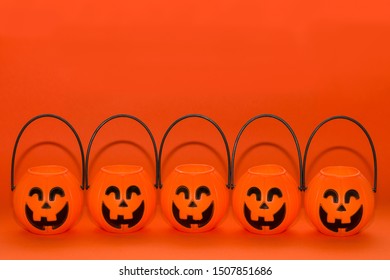 Five Halloween pumpkin baskets. Traditional Halloween party decorations. Orange background.