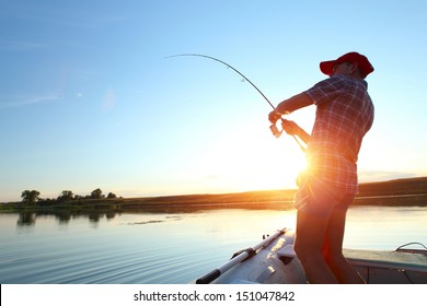 日没時にボートから湖で釣りをする若い男
