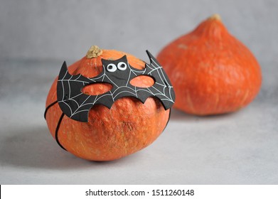 Pumpkin in batman's mask. Behind her is another pumpkin. Halloween holiday attribute. Close-up. Grey background. 