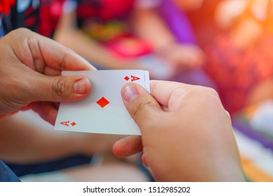Schließen Sie oben von Mannhand, die Spielkarte auf einem unscharfen Hintergrund hält, Ass der Diamanten und König dahinter.