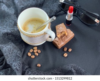 Cappuccino in a white cup red lipstick. Glasses, cosmetics for the lips. Black fabric, lace. Milk chocolate. Coffee beans brown.
