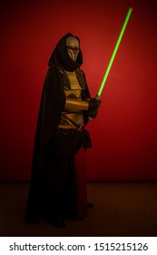 Schauspieler ein Mann in einer Maske und in Kostümen von fiktiven Fantasy-Figuren, die auf einem roten Hintergrund posieren