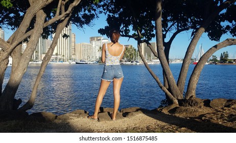 Relaxing young woman with city view at Ala Moana beach, Hawaii.