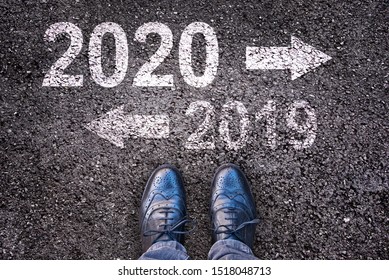 2020 年と 2019 年足でアスファルト道路の背景に書かれた方向矢印