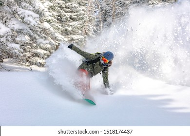 Schior freerider coboară de pe munte. Snowboarderul merge cu snowboard-ul de pe un deal sau munte cu zăpadă pufoasă foarte repede.