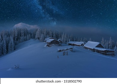 空に魅力的な天の川がある冬のカルパティア山脈のおとぎ話の風景観光用テントと谷にある雪に覆われた家
