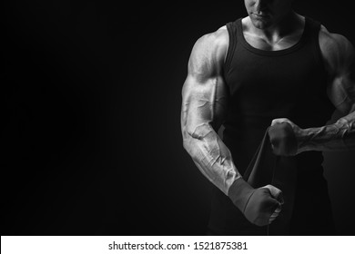 Bodybuilder fitness lifestyle concept Bijgesneden zwart-wit schot op zwarte achtergrond Man is handen inpakken met bokswraps geïsoleerd Sterke handen en vuist, klaar voor training en actieve oefening