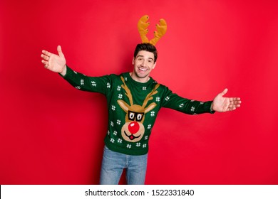 Portrait of excited funky funny man feel crazy hold hands invite on his cool event christmas theme party wear deer reindeer seasonal pattern sweater isolated over red color background