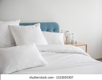 青いベッドに白い枕、羽毛布団、羽毛布団ケース。青いソファに白いベッド リネン。ベッドと寝具を備えた寝室。乱雑なベッド。左側面図。