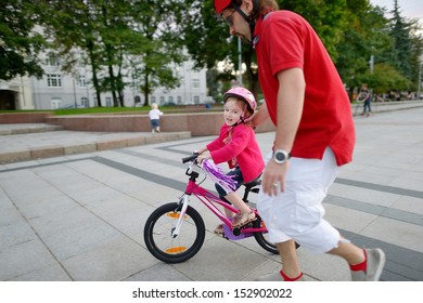 Young father teaching his daughter to ride a bicycle