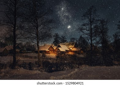 Hermoso paisaje navideño de invierno nocturno. Vista de casas de pueblo nevadas iluminadas por la cálida luz de la ventana. Noche estrellada y una corazonada de Navidad.