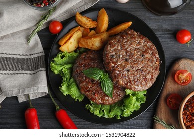 Flache Komposition mit gegrillten Fleischkoteletts für Burger auf schwarzem Holztisch