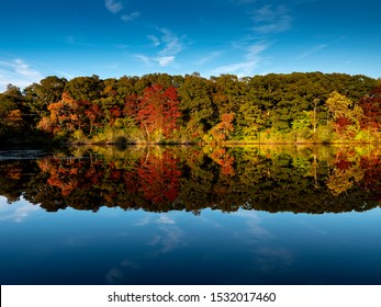 Atemberaubendes Foto von Herbstlaub, das sich auf einem See mit einer spiegelglatten Wasseroberfläche widerspiegelt
