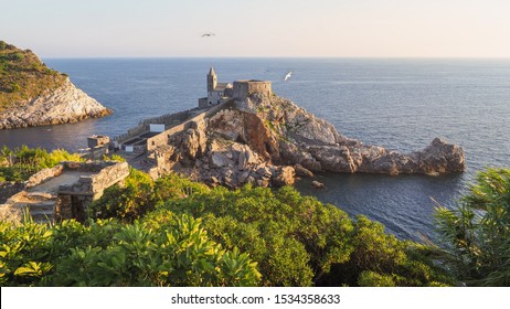 Impresionante puesta de sol en el Golfo de los Poetas. Hermoso paisaje de Porto Venere en Italia. Ruinas del castillo de Doria, iglesia de San Pedro en un acantilado, pequeña isla de Palmaria, mar Mediterráneo y gaviotas.
