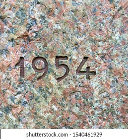 Het jaar 1954 uitgehouwen in graniet en in bruin geverfd - een detail van een inscriptie die dat jaar werd geproduceerd
