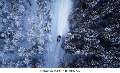 Luchtfoto van een auto op de winterweg in het bos. Luchtfotografie van besneeuwd bos met auto op de weg. Luchtfoto.