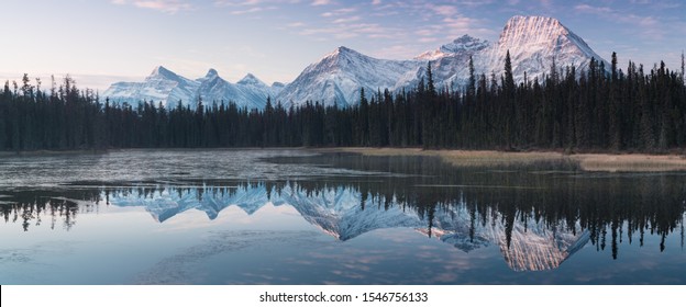 Reflejo casi casi perfecto de las montañas Rocosas en el río Bow. Cerca de Canmore, Alberta, Canadá. Se acerca la temporada de invierno. País de osos. Hermoso paisaje concepto de fondo.