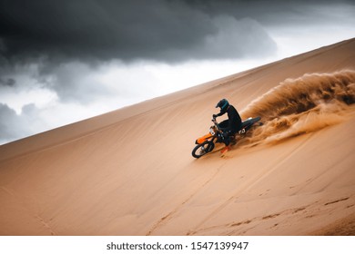 Pengendara sepeda motor dengan sepeda motor lintas alam melaju kencang di padang pasir