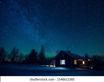 Cottage gegen den Nachthimmel mit der Milchstraße und den arktischen Nordlichtern Aurora Borealis im Schneewinter Finnland, Lappland