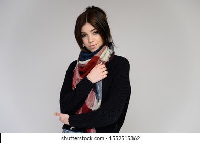 Close-up Portrait einer jungen hübschen Studentin mit langen schwarzen Haaren mit einem Schal und in einem Pullover, auf weißem Hintergrund. In verschiedenen Posen mit Emotionen direkt vor der Kamera stehen.