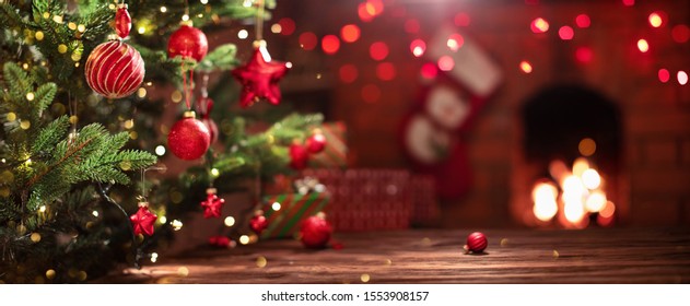 Weihnachtsbaum mit Dekorationen in der Nähe eines Kamins mit Lichtern