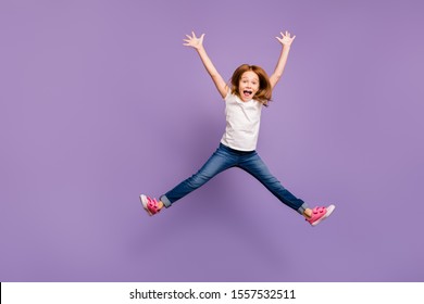 面白い小さなセクシーな女性の完全な長さの写真は、空中で星の形を作る喜びをジャンプして、陽気なクレイジーな気分で、カジュアルな t シャツ ジーンズ分離された紫色の背景を着用します。
