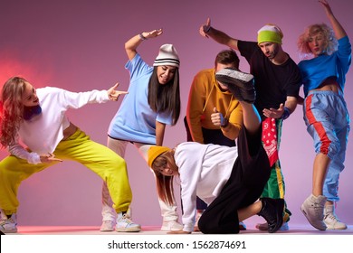 Batalla de hip hop en un espacioso salón de baile, jóvenes bailando break dance, una chica bastante deportiva con una sudadera con capucha blanca y pantalones negros sueltos que muestran una película de baile callejero