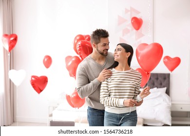 Mooie jonge paar in slaapkamer versierd met hartvormige ballonnen. Valentijnsdag feest