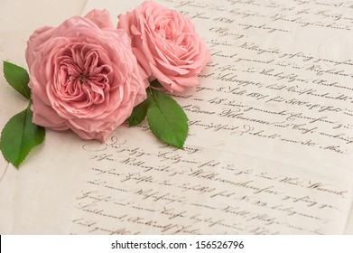 アンティークの手書きの手紙にピンクのバラの花。ロマンチックなビンテージ背景。セレクティブ フォーカス