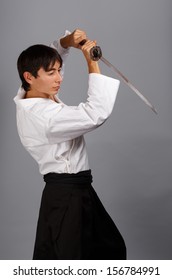 灰色の背景に刀を持って戦うポーズで立っている好戦的な男性