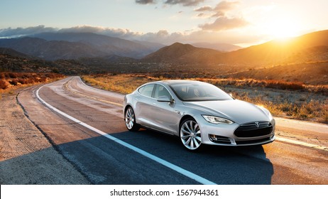Houston, Texas/USA - 22. November 2019: Foto eines grauen Tesla Model S, das auf der Straße fährt, wobei die Sonne im Hintergrund untergeht.