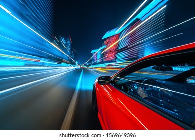 Uitzicht vanaf de zijkant van een rode Muscle Car die in een nachtelijke stad rijdt, Blured-weg met lichten met auto op hoge snelheid. Concept snel ritme van een moderne stad.
