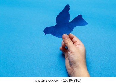 青い背景に青い紙の鳩を持っている子供の手。申し訳ありませんが、あなたは平和を得ます。平和のための世界祈りの日。世界平和記念日。