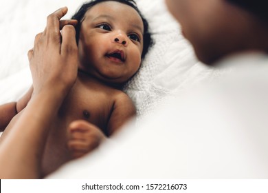 Afroamerikanische Mutter, die mit entzückendem kleinen afroamerikanischen Baby in einem weißen Schlafzimmer spielt. Liebe zum Konzept der schwarzen Familie