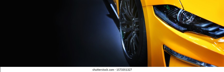 Front headlights of yellow modern car on  black background,copy space

