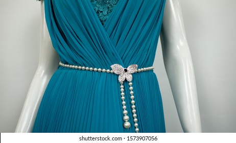 Turquoise Teal Gown Evening Dress on a white mannequin with white opaque pleated curtain background