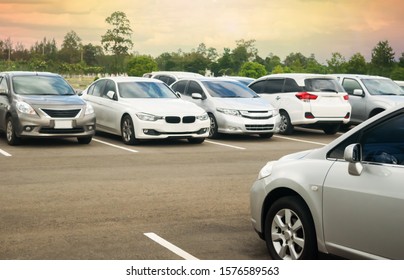 Auto's parkeren op asfalt parkeerplaats met bomen, bewolkte hemelachtergrond in een park. Buiten parkeerplaats met verse ozon, groene omgeving van transport en technologie concept