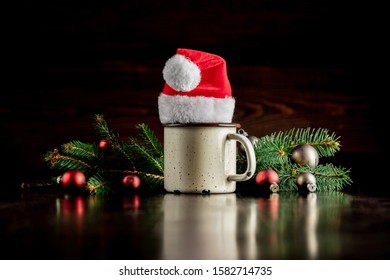 Cup and Santa Claus hat near Christmas tree decoration
