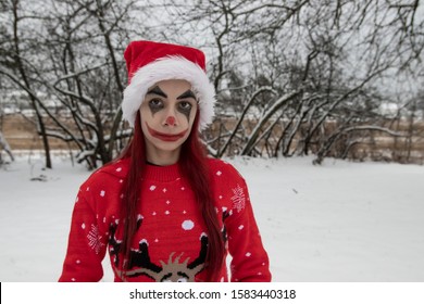 광대 메이크업과 크리스마스 모자를 쓴 소녀.