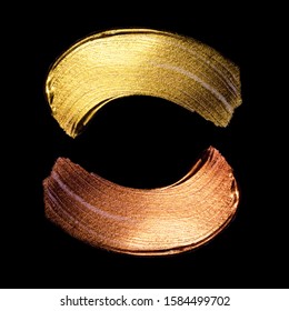 Creatieve penseelstreken van gouden verf geïsoleerd op een zwarte achtergrond. Gouden verf textuur. Acryl gouden verf. Uitstrijkjes van cosmetica, blos, markeerstift, oogschaduw, lippenstift.