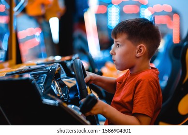 Technologie, Spillerinne, Ënnerhalung a Leit Konzept - glécklech lächelnd Jong a roude T-Shirt mat Spillen Auto Racing Video Spill a Lenkrad.